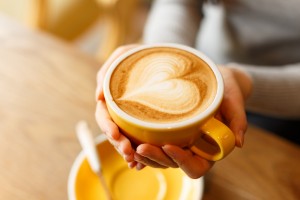lady's hands hold cup filled with something heart-shaped